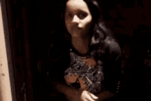 a woman is covering her face with her hand while talking on a cell phone in a dark room .