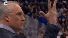 a man in a suit holds his hand up in the air while watching a hockey game