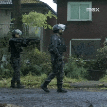 two soldiers are standing in front of a red house with the word max on the bottom