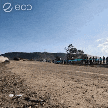 a group of people standing on the side of a dirt road with the word eco on the bottom right
