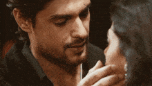 a close up of a man touching a woman 's face while wearing a watch