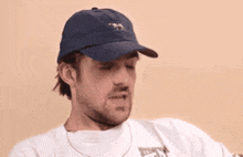a man wearing a white shirt and a blue hat with a horse on it is biting his lip .