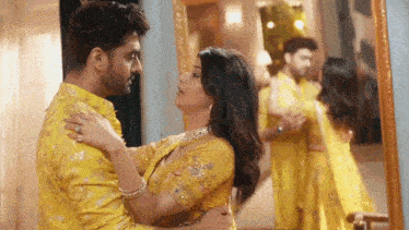 a man and woman are dancing in front of a mirror .
