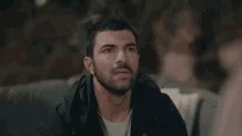 a man with a beard is sitting at a table talking to another man .