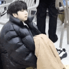 a young boy is sitting on the floor wearing a black jacket and blanket .