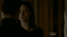 a couple is kissing in a dark room with a cw logo in the corner