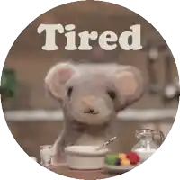 a mouse is sitting at a table with a bowl of cereal and the word tired above it