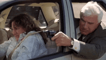 a man is pointing a gun at another man in a car