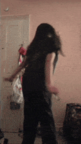 a woman is dancing in front of a door with a bag that has a smiley face on it