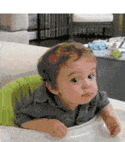 a baby is sitting in a high chair and making a face