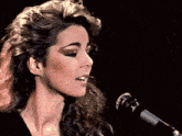 a woman singing into a microphone with a black background
