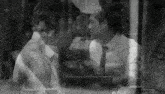 a black and white photo of a man and a woman looking at each other