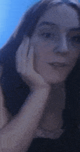 a woman with her hand on her face looks at the camera