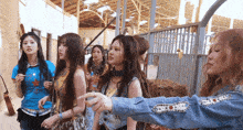 a group of girls are standing in a barn and one of them is pointing