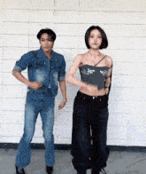a man and a woman are dancing together in front of a white brick wall