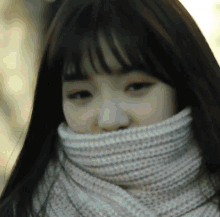 a woman wearing a scarf around her neck covering her face