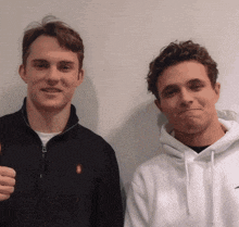 two young men are posing for a picture and one is wearing a black polo shirt