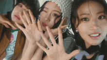 three women are posing for a picture with their hands in front of their faces