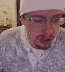 a man with a beard and glasses is wearing a hat and a plaid shirt .