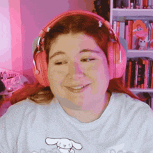 a woman wearing pink headphones and a white shirt with a bunny on it smiles