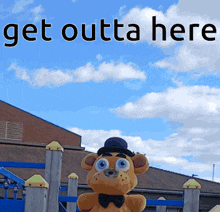 a teddy bear is standing in front of a playground with the words get outta here above it