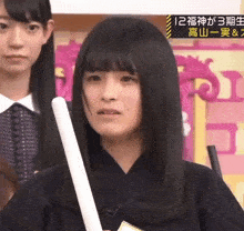 a girl is holding a white stick with chinese writing on it
