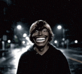a man in a black hoodie is smiling in the dark