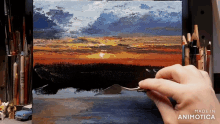 a person is painting a sunset on a canvas with a spoon