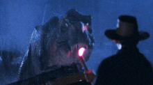 a man in a cowboy hat stands in front of a large dinosaur