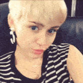 a close up of a woman wearing a striped shirt and earrings