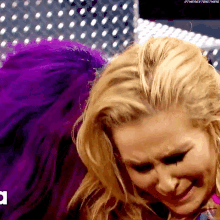 a blonde woman with purple hair is crying in front of a purple background