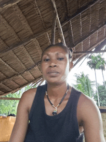 a woman wearing a black tank top and a necklace with a pendant that says a on it