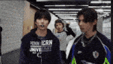 a man wearing a pennsylvania university sweatshirt stands in a hallway