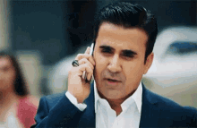 a man in a suit is talking on a cell phone