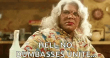 a woman in a wig and glasses is sitting at a table and saying `` hell no . dumbasses unite ... ''