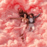 a man and a woman are laying in pink clouds holding glasses of champagne