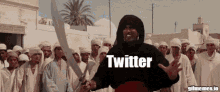 a man is holding a sword in front of a crowd and the word twitter is on the screen