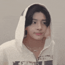 a young man wearing a white hoodie and a necklace