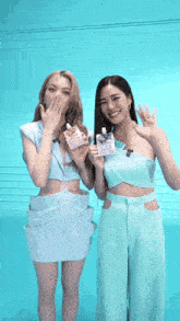 two women are standing next to each other holding bottles of something