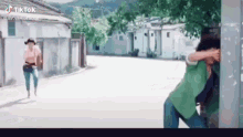 two people are standing next to each other on a street .