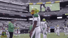 a group of football players standing on a field in front of a large screen that says bullpen