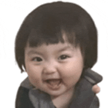 a baby with short hair is smiling and looking at the camera with his mouth open .
