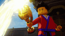 a lego figure is holding a gold trophy in his hand