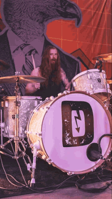 a man playing a drum set with a white drum with a letter d on it