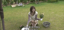 a woman is kneeling down in the grass holding a potted plant in her hand