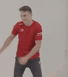 the man is wearing a red shirt and black pants and is dancing .