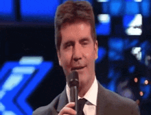 a man in a suit and tie is holding a microphone