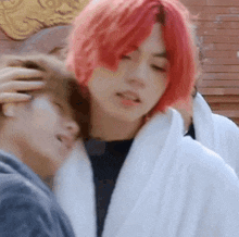 a man with red hair is standing next to another man in a white robe .