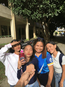 a girl in a blue shirt with the letter o on it takes a selfie