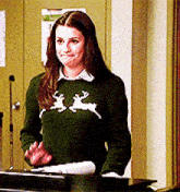a woman wearing a green sweater with reindeer on it is standing at a podium